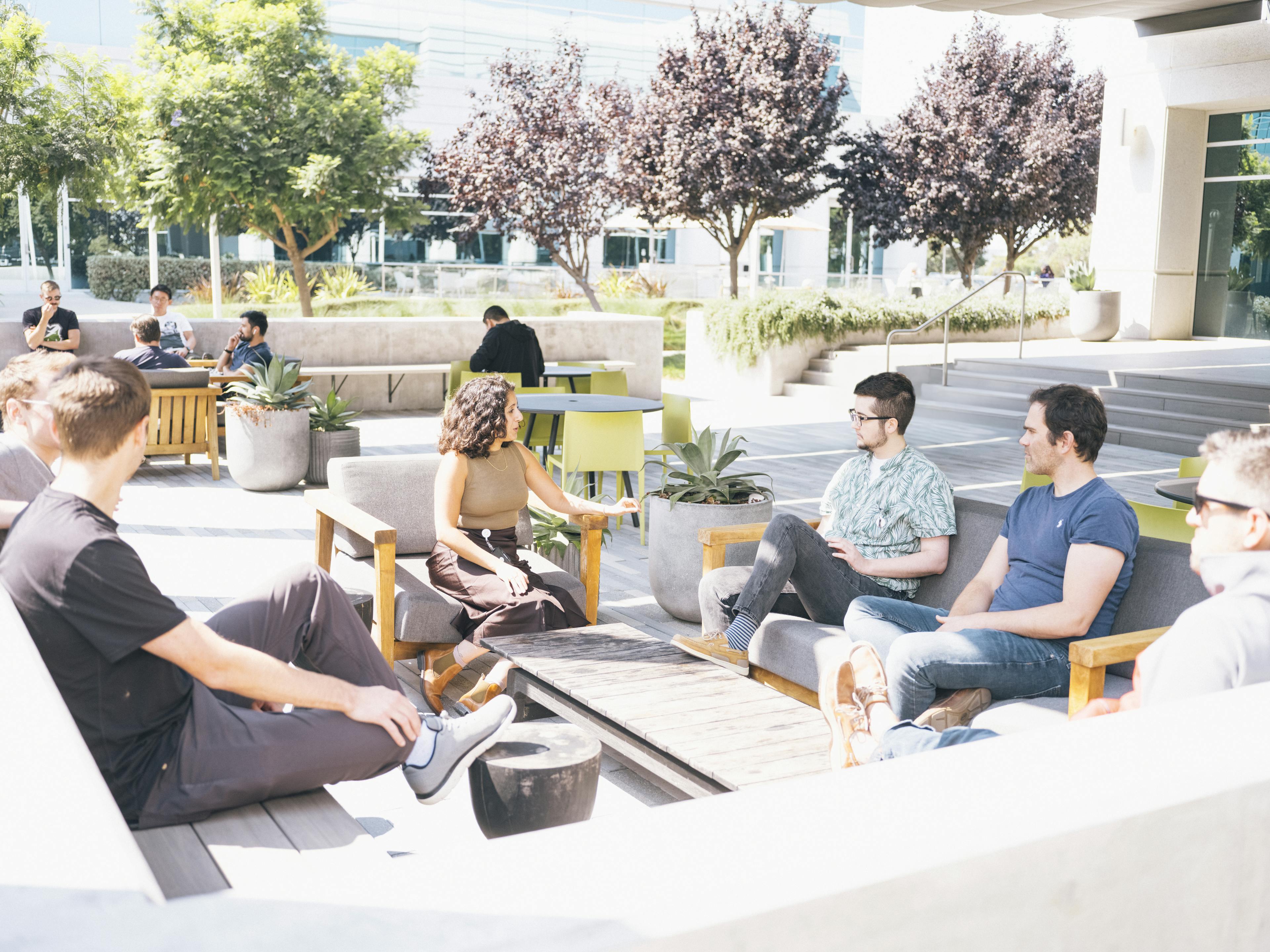 A group of Altos Labs employees sit outside in casual seating having a conversation